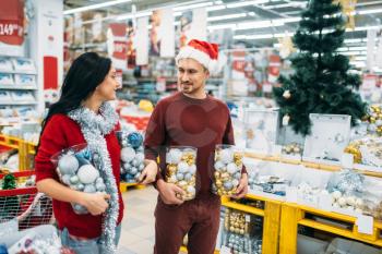 Young couple with boxes full of Christmas balls in shop, family tradition. December shopping of holiday goods and decorations