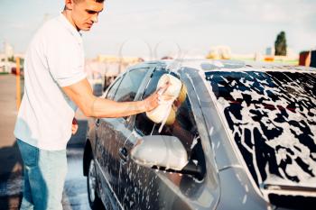 Washer rubbing vehicle with foam, automobile in suds, car wash. Carwashing station