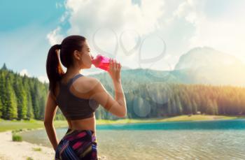 Sporty woman drink water, training on lake shore. Slim girl with sport bottle, outdoor workout