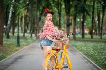 Pin-up girl on retro bicycle, vintage american fashion. Cute woman in pinup style