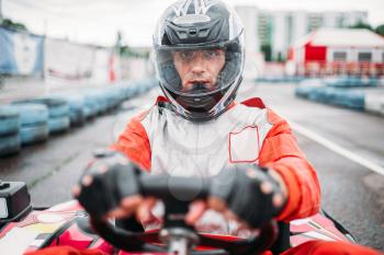 Carting race, go kart driver in helmet on karting speed track, front view. 