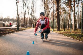 Roller skater in skates, balance exercise on sidewalk in city park. Male rollerskater leisure
