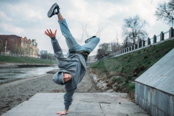 Breakdance performer, upside down motion on the street. Modern dance style. Male dancer