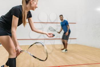 Young couple with rackets play squash game in indoor training club. Active sport lifestyle. Recreation workout, match with racquet