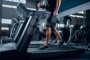 Male person workout on running exercise machine. Active sport training in gym