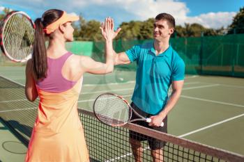 Happy couple with rackets playing on outdoor tennis court. Summer season active sport game