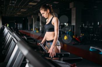 Female athlete exercise on a treadmill in sport gym. Young woman in fitness club