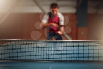 Table tennis net, selective focus, male player on background. Ping pong training indoor