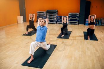 Yoga training, female group with instructor in motion, workout in gym. Yogi exercise indoor