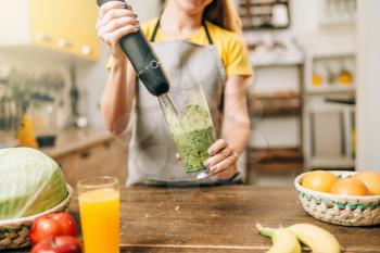 Female person cooking on the kitchen, mixing healthy organic food in a glass. Vegetarian diet, fresh vegetables and fruits on wooden table