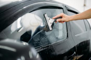 Male specialist work with car window, tinting film installation process, installing procedure, 