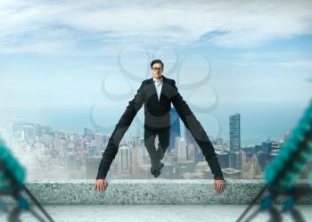 Grasping and tenacious businessman holds on to a roof edge. Success business way concept