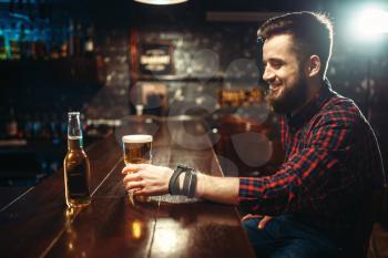 One bearded man drinks beer at the bar counter. Male person leisure in pub