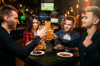 Group of friends having fun in a sport bar and drinks beer, happy football fans