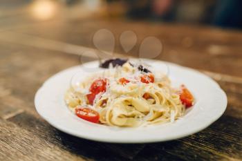 Plate with fresh cooked pasta on wooden table closeup, nobody. Homemade fettuccine, healthy food. Traditional italian cuisine
