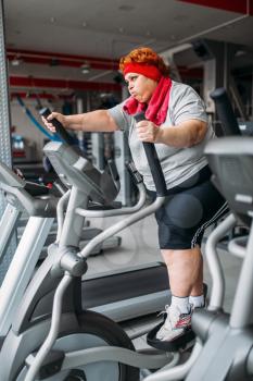 Fat woman using exercise machine for walking, workout in gym. Calories burning, obese female person in sport club, fat people