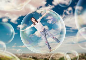 Pretty woman flying in the sky in big soap bubble. Female person in large air balloon