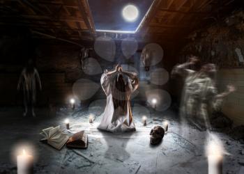 Witch in white shirt, flying spirits of dead people, pentagram circle with candles in basement of the abandoned house, dark magic ritual in full moon, witchcraft. Occultism and exorcism