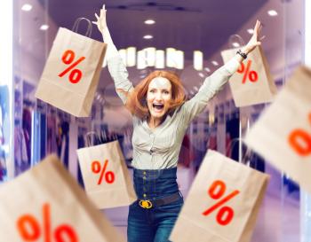 Joyful woman among sale paper bags in store. Female person with paperbags in mall, shopping time. Discount concept