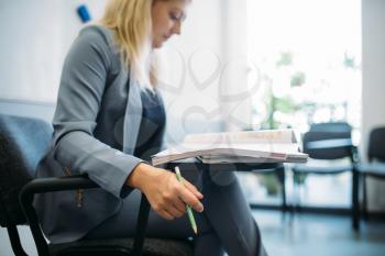 Woman in suit at the interview in business office. Secretary or manager conducts negotiations sitting on a chair. Job search or head hunting concept