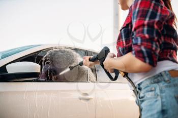 Female person wash off the foam from the car glass. Woman on self-service automobile washing. Outdoor vehicle cleaning at summer day 