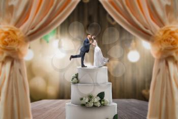 Wedding cake with bride and groom on the top. Pie for newlyweds with little figurines, love symbol