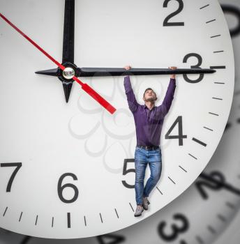 Man hangs on the arrow of a huge clock. Deadline concept, time does not stop