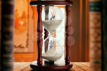 Man and woman drowning inside an hourglass, deadline concept, bookshelf on background