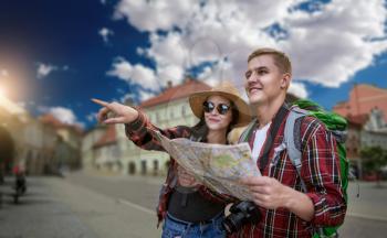 Hikers with backpacks looking for city attractions on the map, excursion in tourist town. Summer hiking. Hike adventure of young man and woman