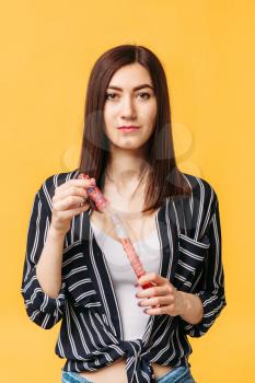 Beautiful woman with soap bubble, yellow background. Female person blowing colorful balloons