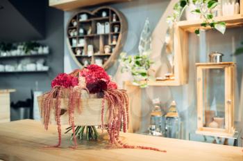 Fresh red flower bouquet with decoration on the table in shop, nobody. Floral composition in boutique, professional floristic service