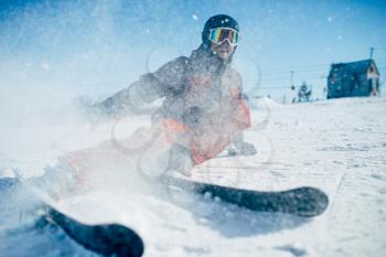 Skier in helmet and glasses lies on snowy surface of speed slope, front view. Winter active sport, extreme lifestyle. Downhill skiing