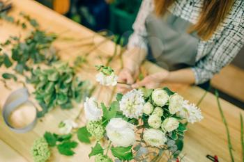 Female florist with pruner in hands makes flower bouquet. Floral business, decoration tools