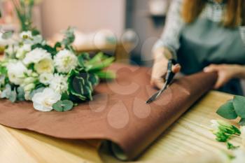 Female florist hands cuts flower decoration with scissors. Floral business, bouquet preparation process