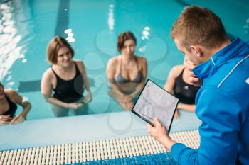 Female group with male trainer, aqua aerobics in swimming pool. Women in swimwear on training, water sport 