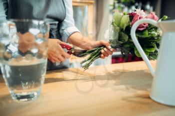 Female florist making flowers arrangement on the table in shop. Floral artist decorates bouquet at the workplace
