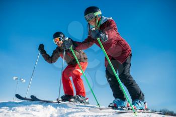 Male and female skiers racing from the mountain, side view. Winter active sport, extreme lifestyle. Downhill skiing