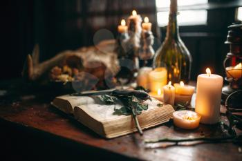 Witchcraft, dark magic, candles with ritual book on the table, nobody. Occult and esoteric symbols