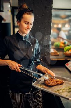 Female cook holds fresh prepared steak, grilled meat. Beefsteak cooking, food preparation on kitchen