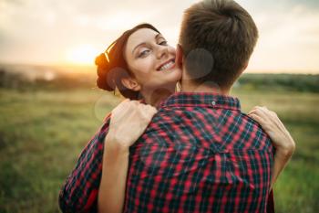 Love couple hugs together on the meadow at sunset. Romantic junket of man and woman, picnic in the field
