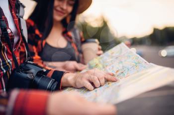 Tourists study the map of city attractions, excursion in town. Summer hiking. Hike adventure of young man and woman