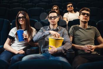 People in 3d glasses with popcorn and drinks watching movie in cinema. Entertainment business