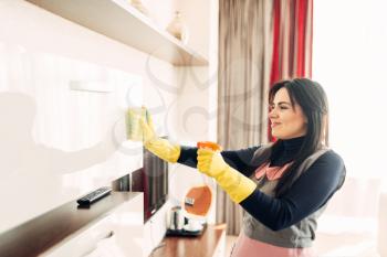 Housemaid hands in gloves cleans furniture with a cleaning spray, hotel room interior on background. Professional housekeeping