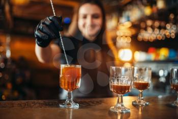 Female bartender making coctail at the bar counter. Alcohol drink preparation. Barman working in pub
