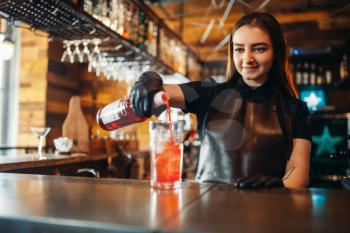 Female barman prepares alcoholic coctail with ice. Alcohol drink preparation. Woman bartender working at the bar counter in pub