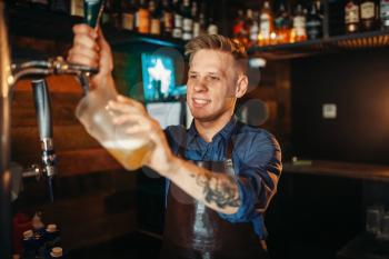 Male barman pouring beer at the bar counter. Barkeeper occupation, bartending