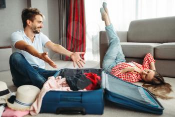 Young couple packing their suitcases for vacation. Fees on journey concept. Luggage preparation