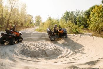 Two atv riders in helmets running laps on sand, offroad in forest. Riding on quad bike, extreme sport and travelling, quadbike adventure