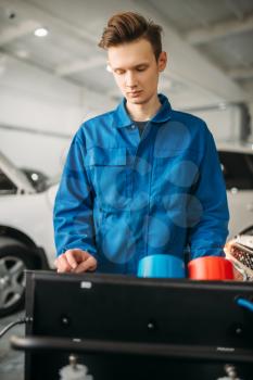 Mechanic stands at the air conditioning diagnostic system. Conditioner inspection in car service