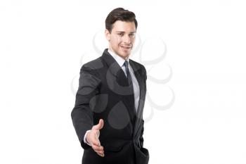 Young businessman in tie and black suit extends his hand, isolated on white background